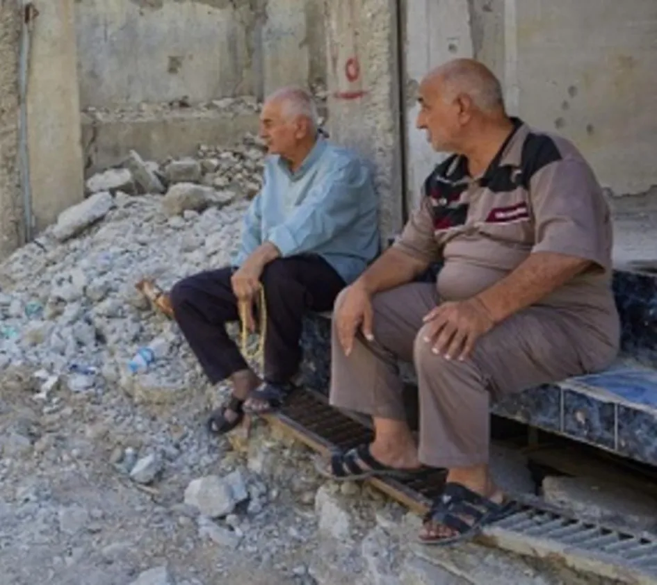 Leid: Zwei Männer sitzen auf den Stufen eines zertrümmerten Gebäudes