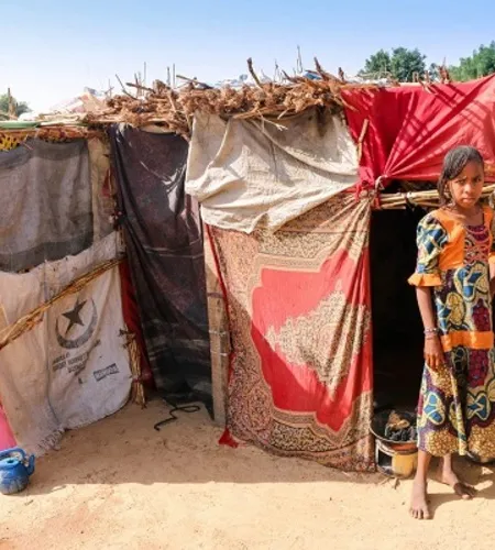 Nigerianisches Mädchen vor farbenfrohem aber provisorischem Zelt
