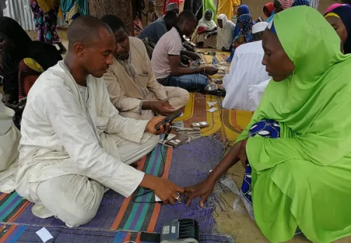 Mann händigt Gutschein an eine Frau im grünen Gewand aus