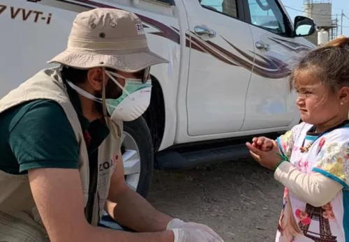 ZOA worker wearing a face mask stops to talk to a girl